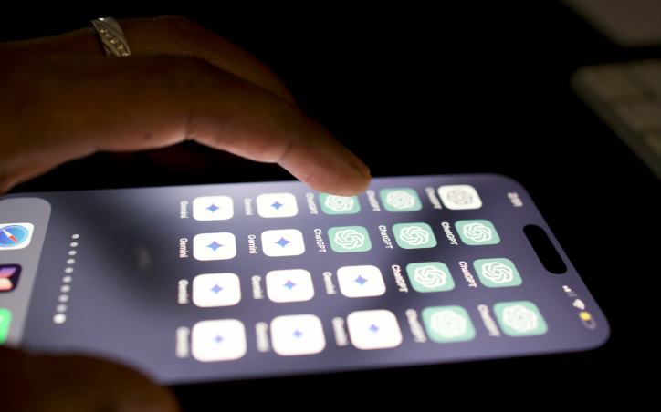 Close-up of a hand using a phone displaying AI apps on its home screen